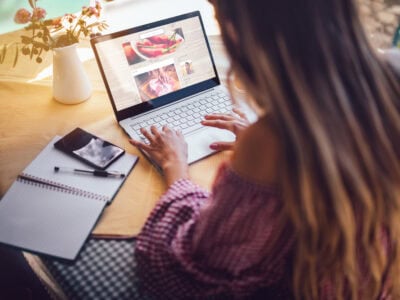 Young food blogger entrepreneur writing blog post and working online on laptop from home office