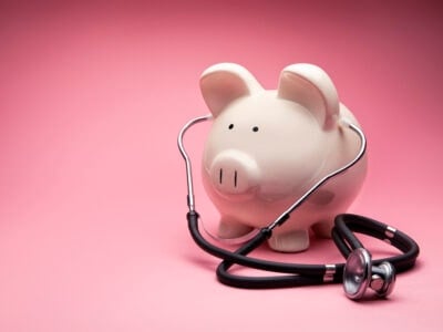 This is a photo of a large white piggy bank on a pink background. This is a concept photo related to finance and the medical hospital industry,